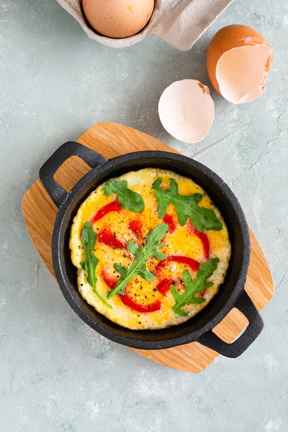 Omelette with fresh pepper and arugula. Frittata in frying pan. - Photo, image