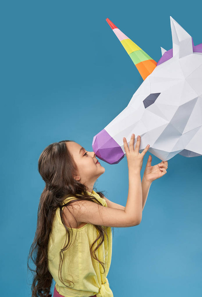 Chica sosteniendo 3D cabeza de unicornio y tocando la nariz
. - Foto, Imagen