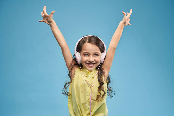 Happy girl listening music in headphone and raising hands up - Фото, изображение