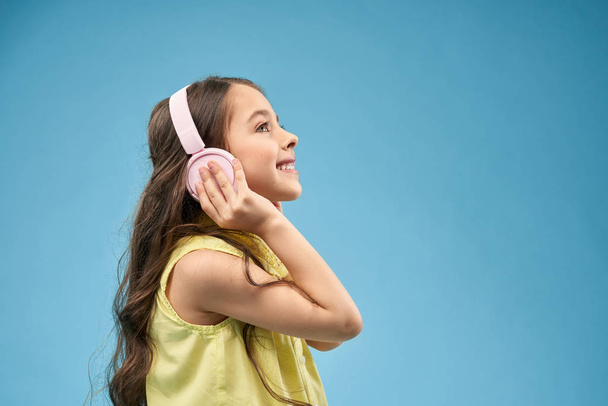 Happy little girl with long hair in pink headphones smiling. - Photo, image