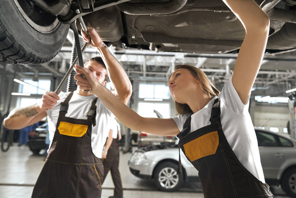 Woman and man working in autoservice as mechanics. - Photo, image