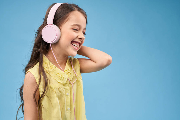 Весела дитина в рожевих навушниках посміхається і позує
. - Фото, зображення