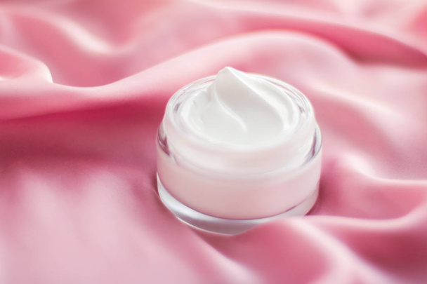 Frasco de crema facial de lujo sobre una suave seda rosa
 - Foto, imagen