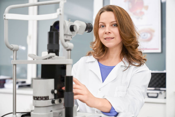 Female ophthalmologist posing with eye test machine. - Fotoğraf, Görsel