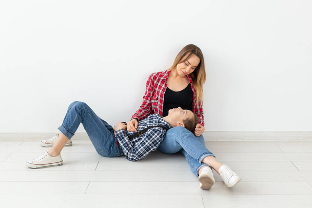 Familie, Muttertags- und Teenager-Konzept - Porträt von Mutter und Sohn auf dem Fußboden sitzend - Foto, Bild