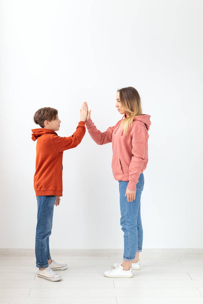 Relatie, Moederdag, kinderen en familie concept - moeder en zoon gekleed in sweatshirts, hoge vijf gebaar - Foto, afbeelding