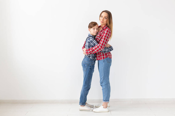 Dia das mães, crianças e conceito de família - menino adolescente abraçando sua mãe no fundo branco com espaço de cópia
 - Foto, Imagem