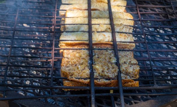 Traditional South African toasted sandwiches known as braai broodjies prepared on an open fire image with copy space in landscape format - Photo, Image