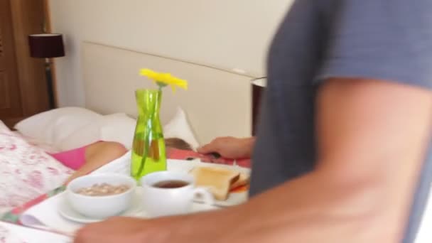 Man places tray with breakfast in front of woman - Πλάνα, βίντεο