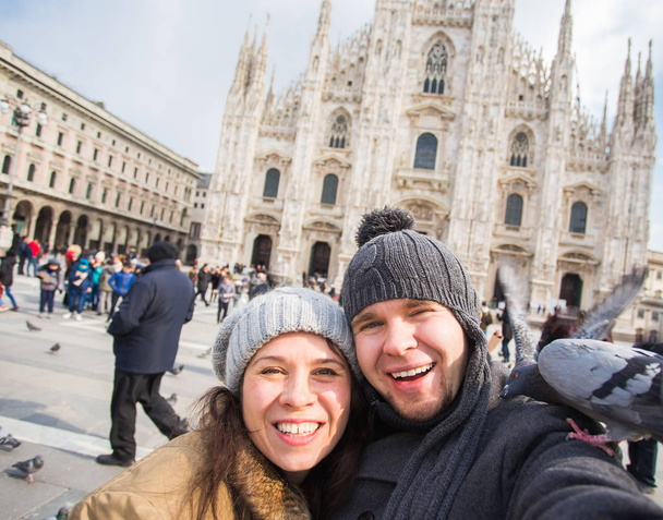 Ταξίδια, Ιταλία και αστεία ζευγάρι έννοια - χαρούμενων τουριστών λήψη αυτοπροσωπογραφία με περιστέρια μπροστά στον καθεδρικό ναό Duomo, Μιλάνο - Φωτογραφία, εικόνα
