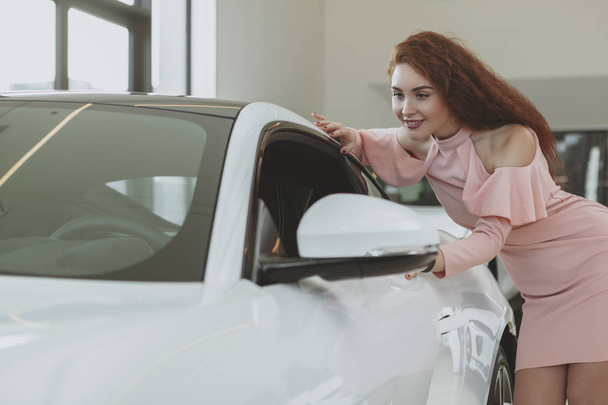 Young businesswoman shopping for new car at dealership showroom - Foto, imagen