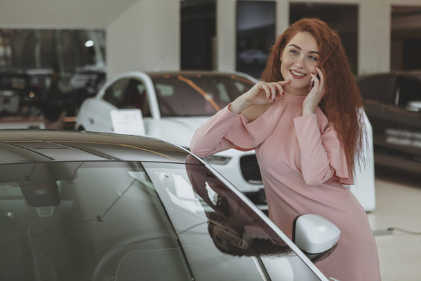Attractive woman using her smart phone while bying new car - Foto, Bild