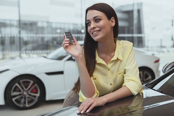 Happy woman holding car keys to her new automobile - Foto, imagen