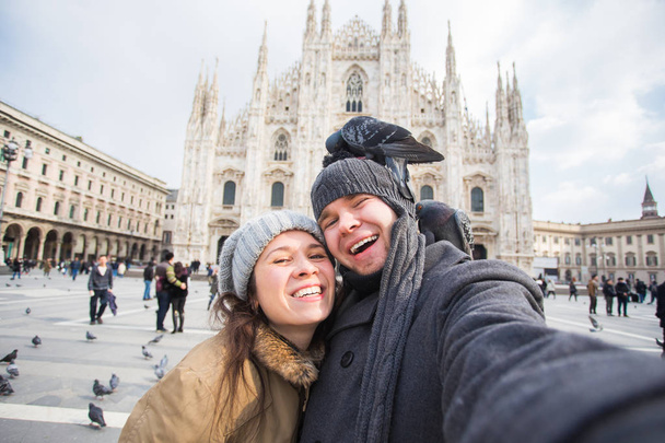 Paar nemen Zelfportret met duif op het plein van de Duomo in Milaan. Winter reizen, Italië en relatie concept - Foto, afbeelding