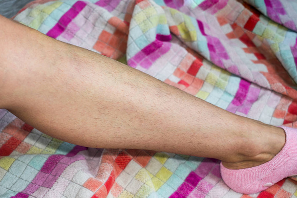 Nainen ja hänen karvainen jalkansa monivärisessä pyyhkeessä. Tyttö antiikissa
 - Valokuva, kuva