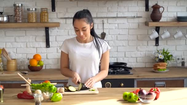 Happy, young couple. Woman cutting eggplant. Man having fun and taking peace of it from cutting board. - Séquence, vidéo