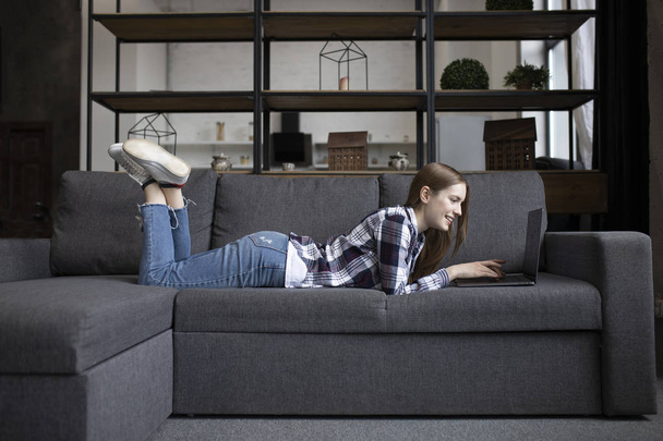 Portrait of cute girl with laptop on sofa - Foto, imagen