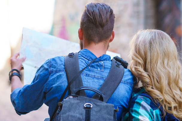 Jonge reizigers verkennen richtingen met een toeristische kaart. Man en vrouw met vakantie. Backpackers, reizen en toerisme concept. - Foto, afbeelding