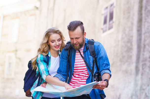 Young travelers exploring directions with a tourist map. Man and woman having vacation. Backpackers, traveling and tourism concept. - Photo, Image