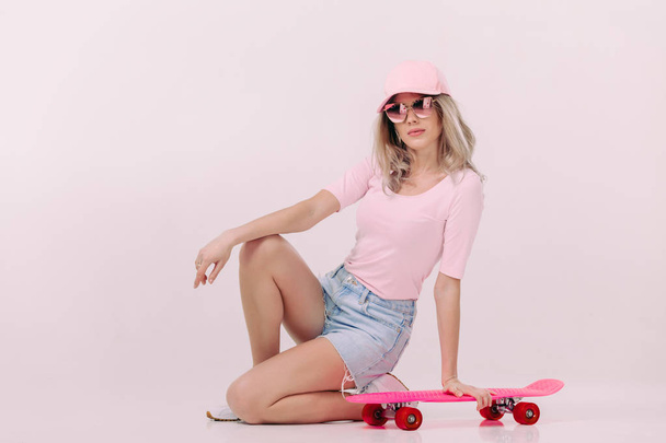 beautiful woman in white t-shirt with pink skateboard - Фото, зображення