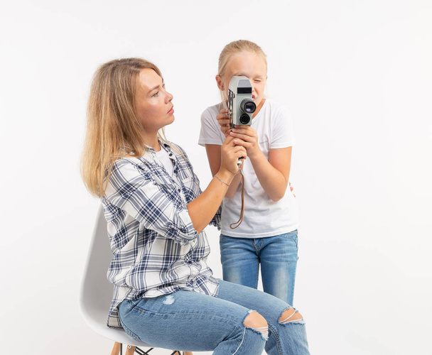Perhe, valokuvaus ja harrastus konsepti nainen ja hänen lapsensa käyttäen vanhanaikaista kameraa valkoisella taustalla
 - Valokuva, kuva