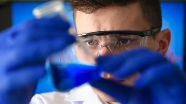 Científico hombre en gafas protectoras estudia muestra en tubo de ensayo. Concepto de investigación médica
 - Metraje, vídeo