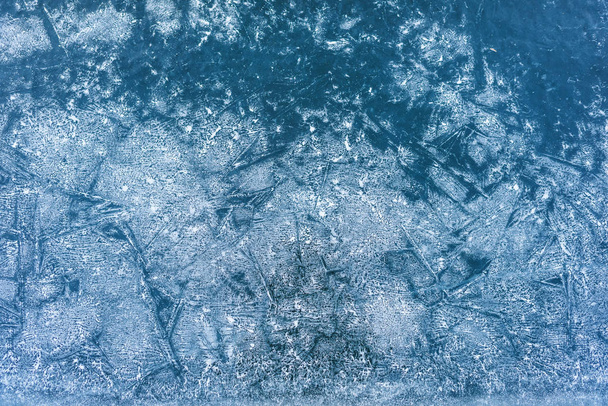 凍結する水の表面。山の湖で氷します。氷にひびが入った。凍った湖の表面にひびが入った。氷の上は雪します。氷の中の気泡。水の凍った地表のテクスチャ. - 写真・画像