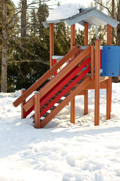 Lumineux rouge en bois personne aire de jeux pour enfants avec une glissière pour l'activité jeux pour enfants en hiver sur la neige autour
 - Photo, image