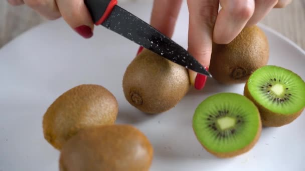 Kobiecych rąk wyciąć kiwi z nożem, z bliska - Materiał filmowy, wideo