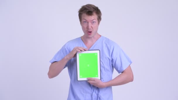 Crazy young man patient showing digital tablet and looking shocked - Materiaali, video