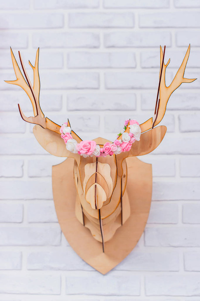 White brick wall. Wooden deer head. Wall decoration. Paper garland in the shape of hearts. Artificial flowers. Decorative element. The interior of the room. - Valokuva, kuva