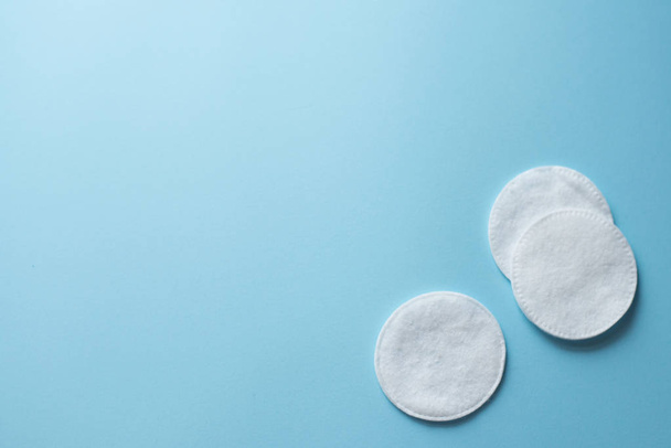 Clean white cotton stack of disk for beauty face hygiene with selective focus on blue neutral background. Cosmetic softness pure sponge for makeup remover. Sterile cleanliness facial sponges - Foto, afbeelding