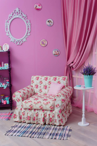 The wall is lilac. Wooden floor shelf.  Decorative element. Lavender in a blue pot. White round table. Pink curtains. Wooden panels on the wall. White chair with floral print. - Zdjęcie, obraz