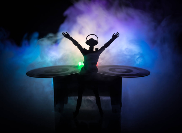 dj club konzept. Frau DJ Mixing, und Kratzen in einem Nachtclub. Mädchensilhouette auf dem DJ-Deck, Blitzlicht und Nebel im Hintergrund. Kreative Kunstwerke Dekoration mit Spielzeug. Selektiver Fokus - Foto, Bild