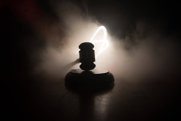 Law theme, mallet of the judge on wooden desk with Lady Justice Statue. Law gavel on dark foggy background with light. Selective focus - Photo, Image