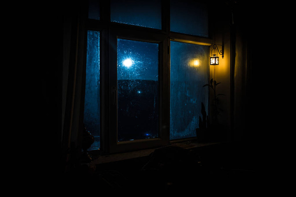暗い部屋の窓から見た月の夜のシーン。夜空古いビンテージ ランタンを持つウィンドウから表示暗い部屋の中。長時間露光ショット - 写真・画像