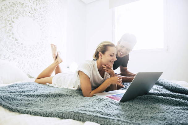 fiatal pár szóló ágy, és dolgozik a laptop a hálószobában - Fotó, kép