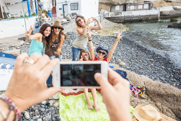 Gruppe kaukasischer Freundinnen genießen die Freizeitaktivität im Freien am Strand und machen Fotos, um sie in den sozialen Medien zu teilen - lachen in Freundschaft und nutzen das Technologiekonzept - Foto, Bild
