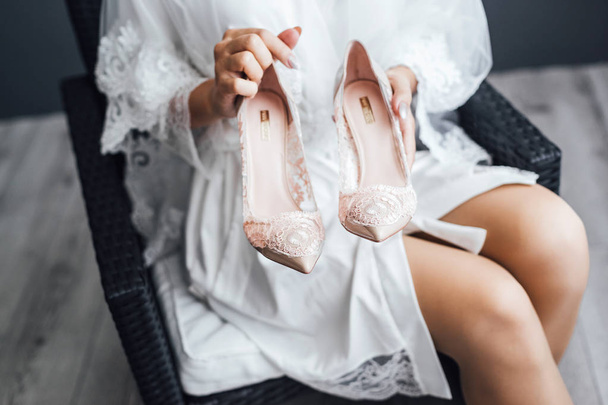 Cropped view of bride holding elegant wedding shoes - 写真・画像