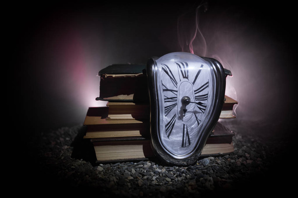 Zeitkonzept. verzerrte weiche schmelzende Uhr auf den alten Büchern. mit dunkel getöntem Nebelhintergrund. Selektiver Fokus - Foto, Bild