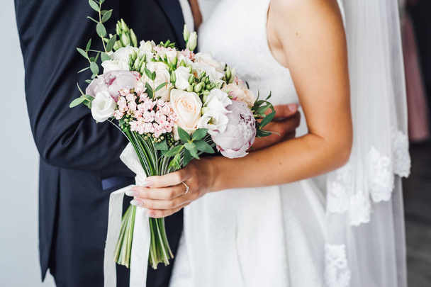 Przycięte widzenia pana młodego i panny młodej w sukni ślubnej, trzymając elegancki kwiaty - Zdjęcie, obraz