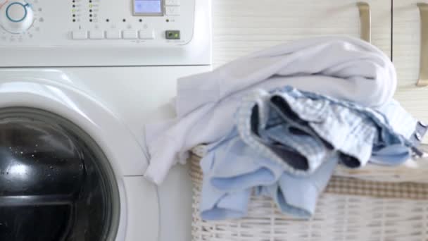 Wasserij wordt gewassen in de wasmachine, en schone dingen zijn op de mand in de buurt. - Video