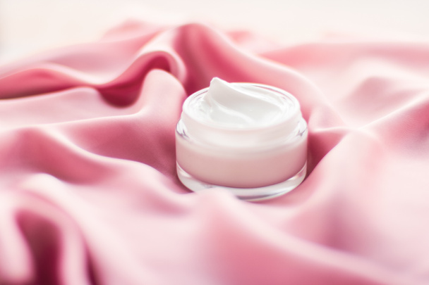 Luxe gezichtscrème pot op een zacht roze zijde - Foto, afbeelding
