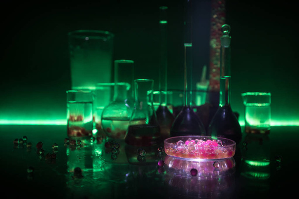 Eczane ve kimya teması. Araştırma laboratuarında çözeltisi olan cam deney şişesi. Bilim ve tıbbi geçmiş. Koyu renk arkaplan üzerinde laboratuvar test tüpleri, bilimsel araştırma ekipmanları konsepti - Fotoğraf, Görsel