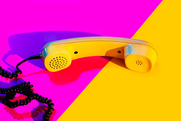 Ρετρό vintage τηλέφωνο ακουστικό κίτρινο ροζ κόκκινο μωβ πλαστικό πορτοκαλί ντίσκο φόντο παλιό στυλ σκιά 90 - Φωτογραφία, εικόνα