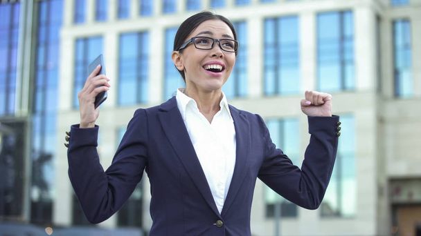 Happy young lady showing success sign, receiving job offer, successful startup - Фото, изображение