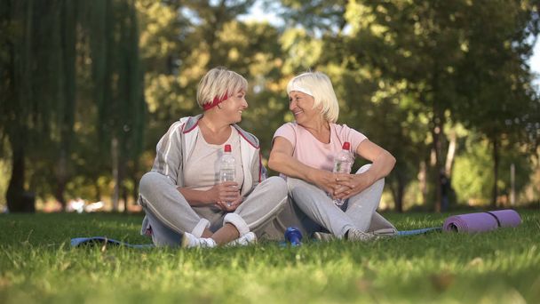 Le donne che chattano seduti sull'erba dopo le lezioni di yoga all'aria aperta, assistenza sanitaria
 - Foto, immagini