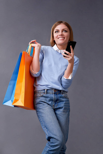 Young woman talking on your smartphone standing with colored bags for shopping. - Foto, Imagem