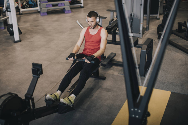 Top näkymä urheilullinen mies tekee liikuntaa selässä voimistelu kone kuntosalilla klubi
 - Valokuva, kuva
