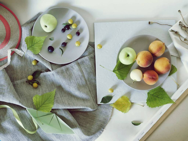 Peaches, apples, plums, leaves on plates on a light background, top view, summer, autumn season, fruit harvest, lifestyle, healthy food - Φωτογραφία, εικόνα